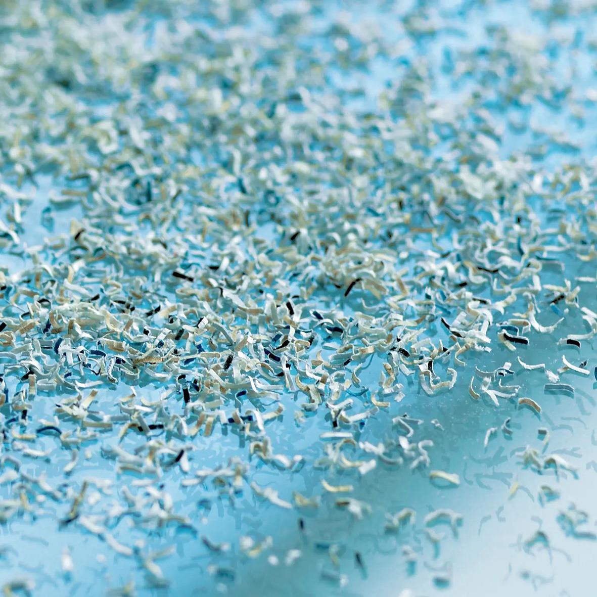 Mängd av pappersrester från en dokumentförstörare på en blå yta