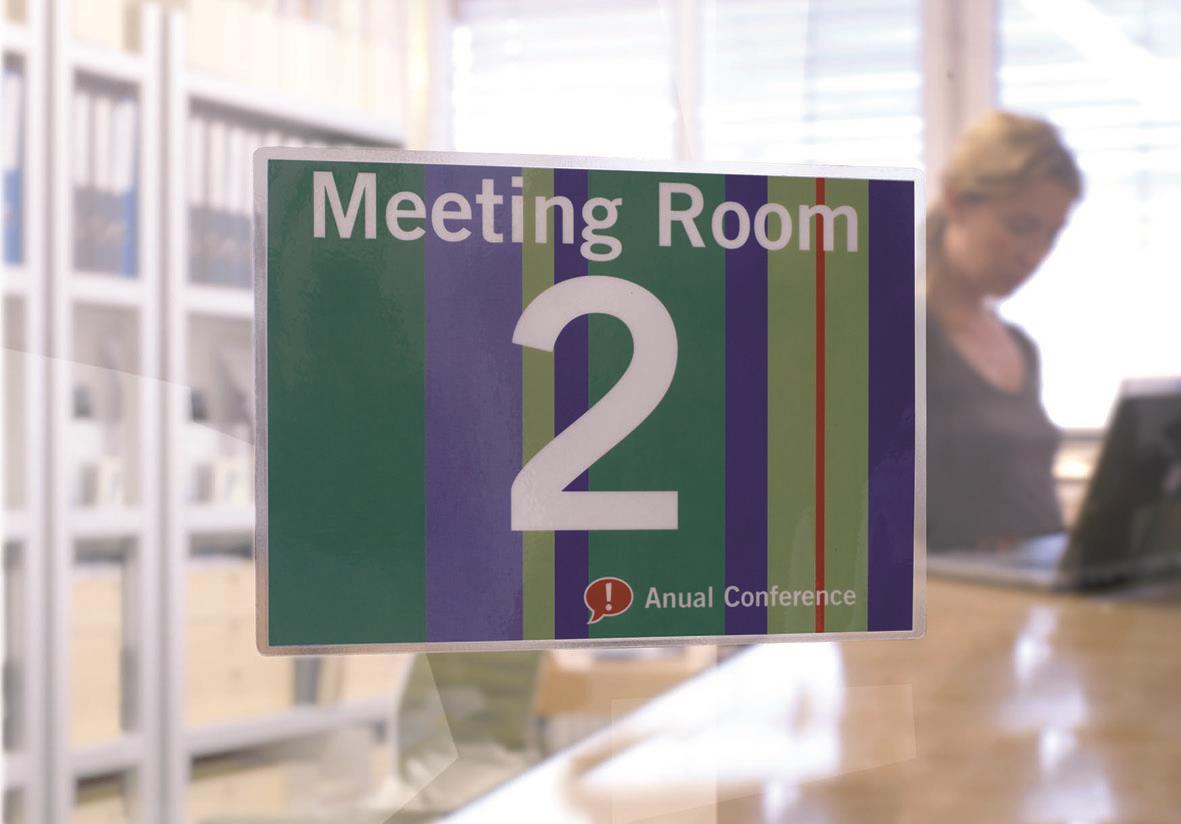 Skylt för mötesrum 2 med text Meeting Room 2 och färgade linjer, i kontorsmiljö