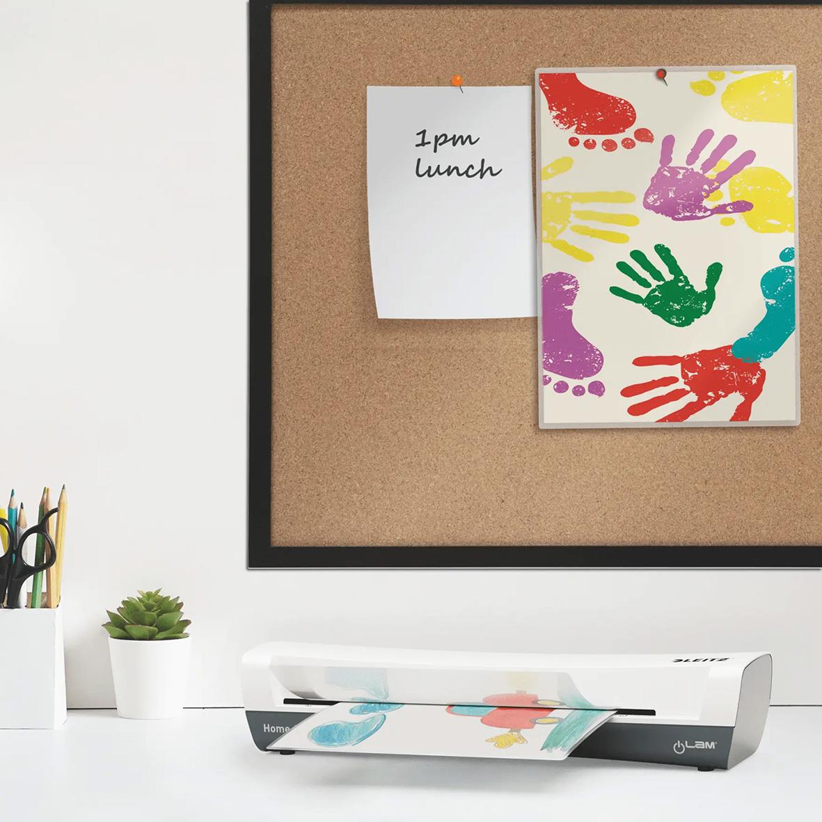 Lamineringsmaskin Leitz iLam Home A3 vit på skrivbord med papper och växt