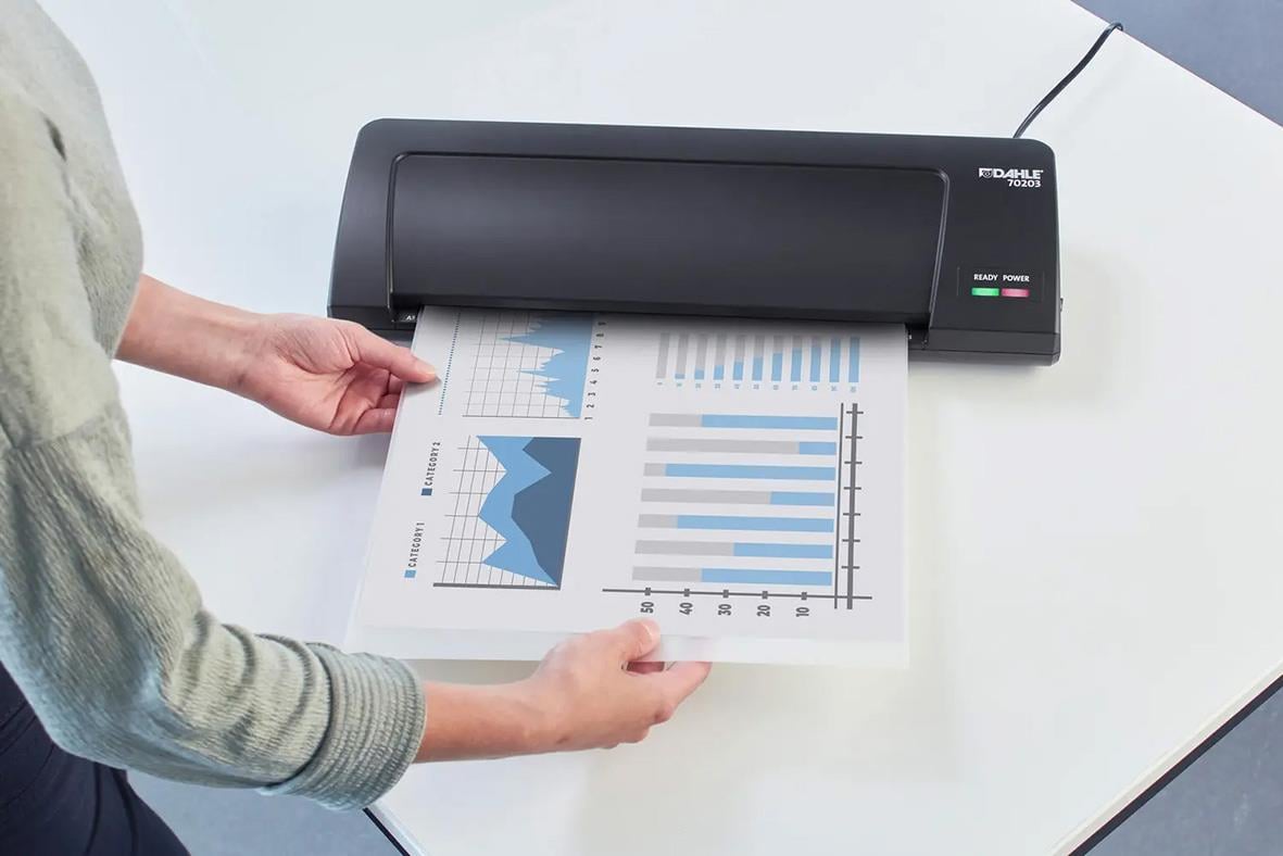 Person laminera ett dokument med Dahle 70302 A3 lamineringsmaskin på ett skrivbord