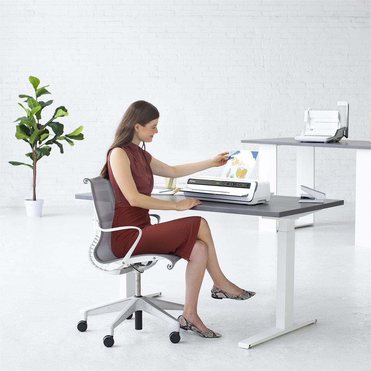 Kvinna laminering med Fellowes Venus A3 lamineringsmaskin på kontorsbord