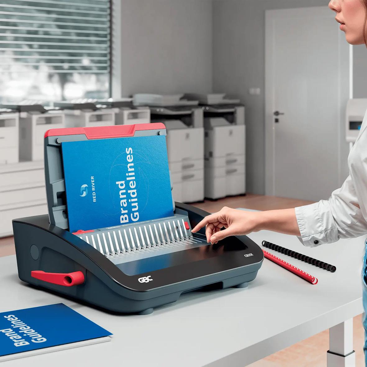 Spiralinbindningsmaskin GBC CombBind CB25E på skrivbord med hand som använder den