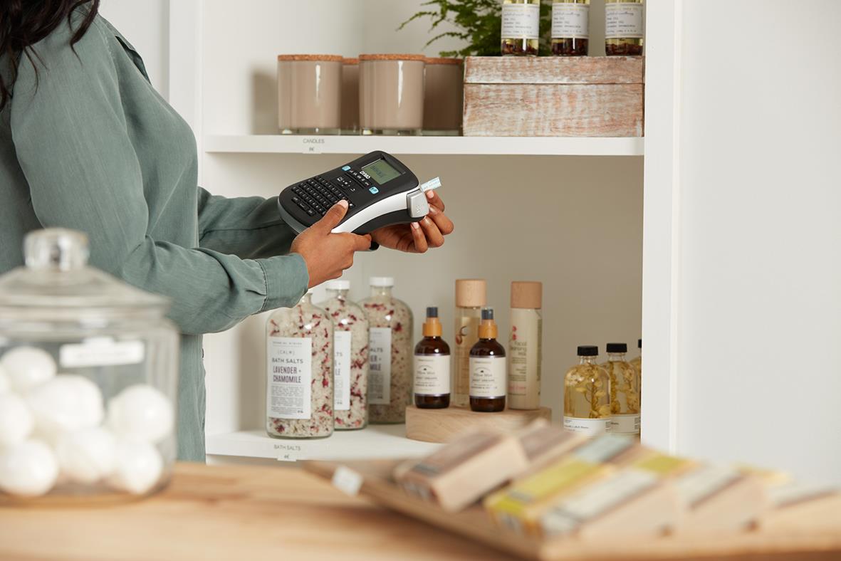 Person som använder en Dymo LabelManager 210D märkmaskin i ett kök eller arbetsrum