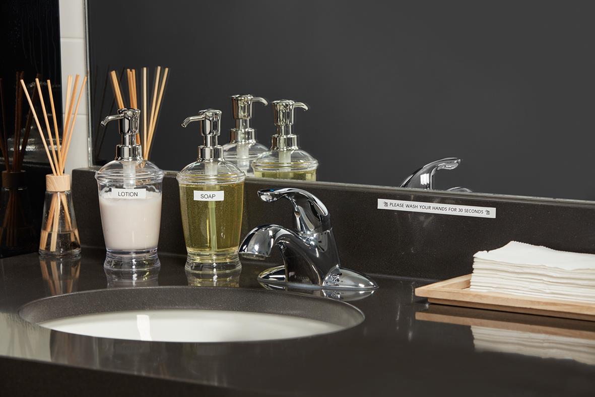 Badrum med tvål, handdesinfektion och pappershanddukar på svart bänkskiva