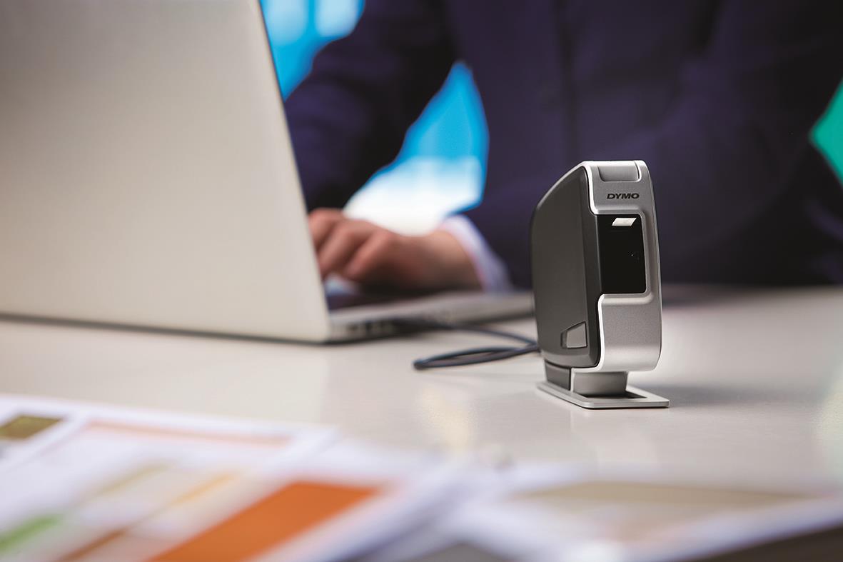 Dymo LabelManager Pnp märkmaskin på skrivbord med person i bakgrunden