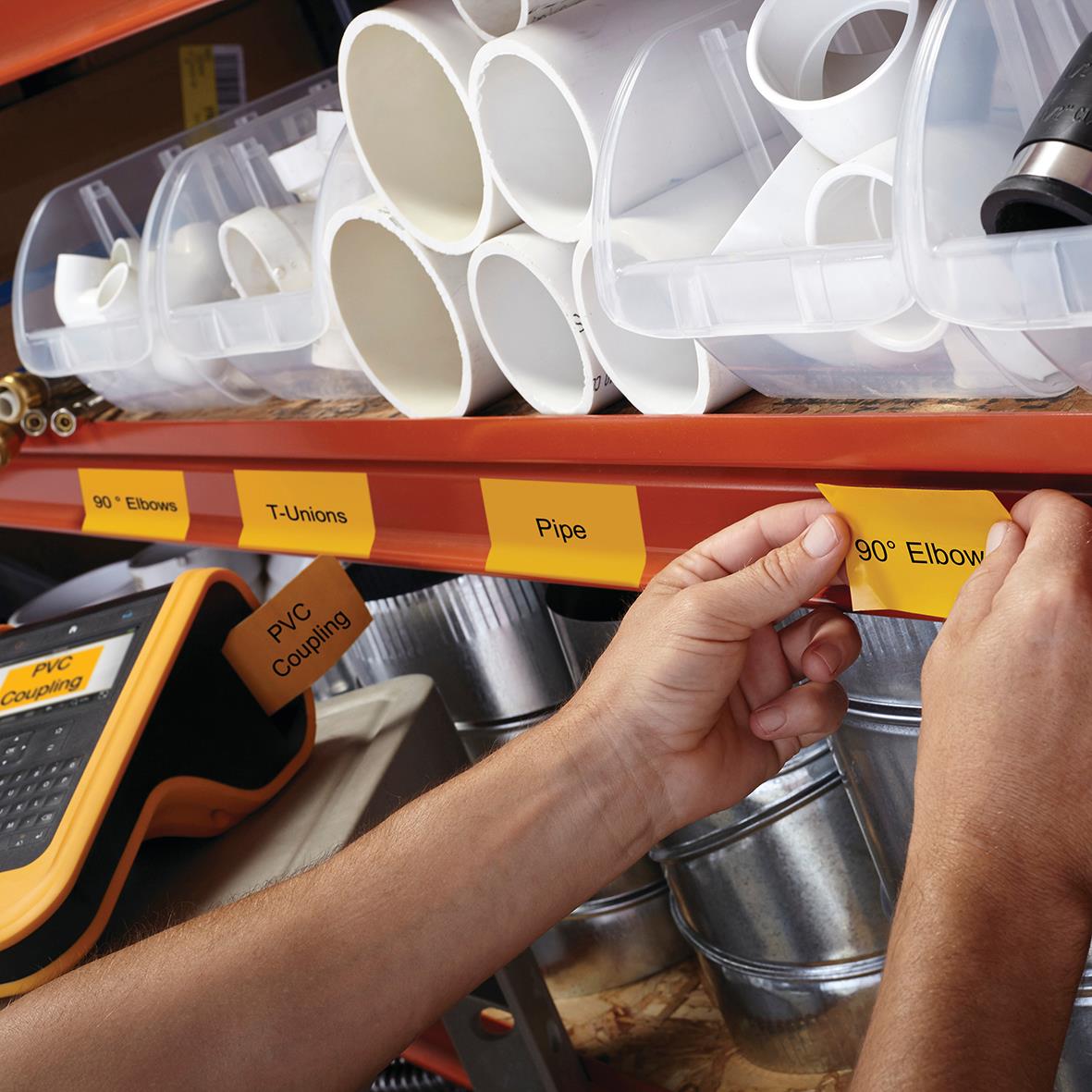 Person märker upp rör och delar i en verktygs- eller lagringshylla med gula etiketter