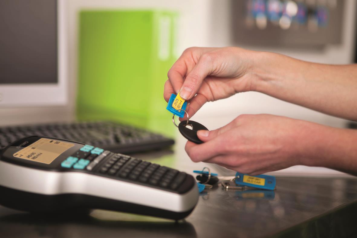 Person som byter batteri i Dymo LabelManager 420 etikettmaskin med väskkit på skrivbordet