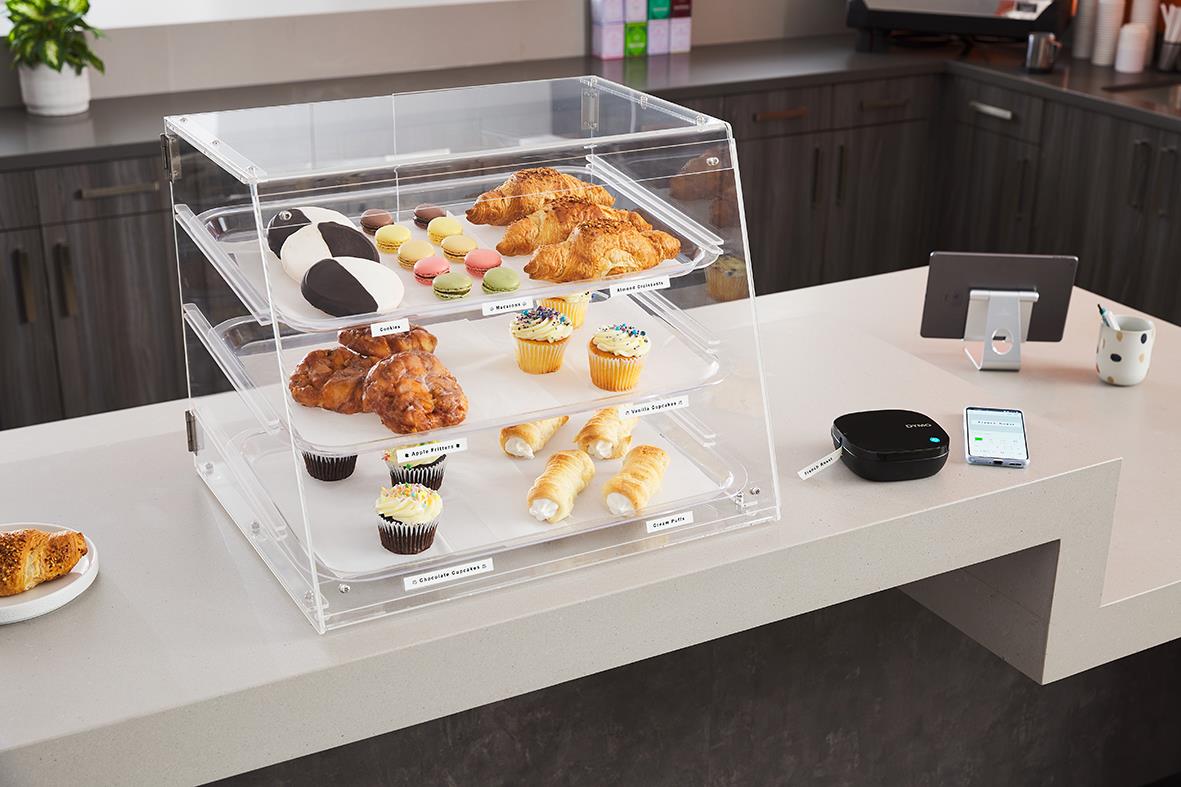 Trevåningsdisplay med bakverk och cupcakes på ett vitt bord i ett kök