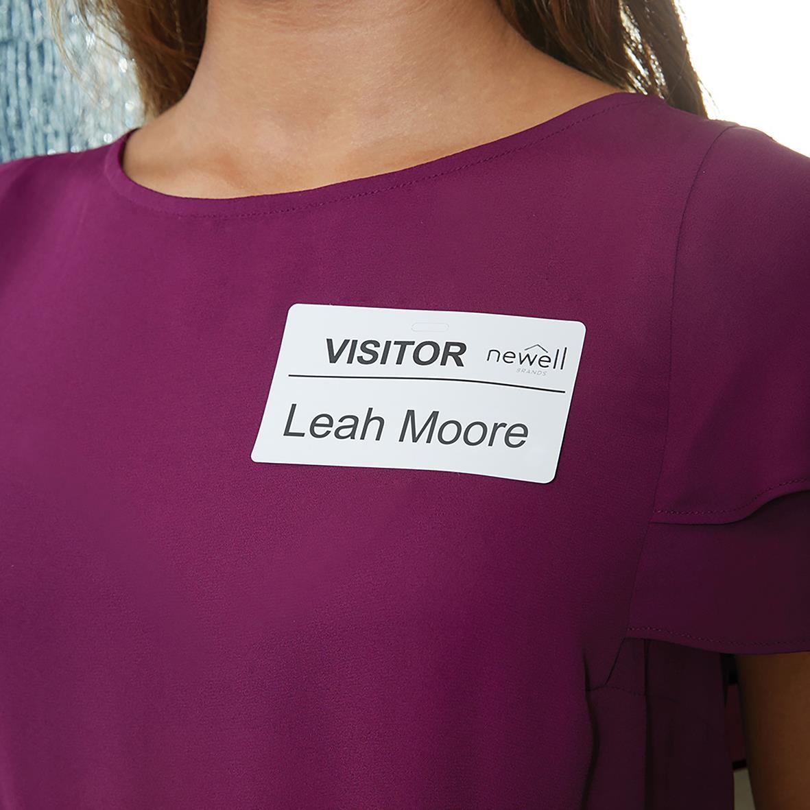 Namnnamn på vit etikett på en persons klänning, text: VISITOR newell Leah Moore