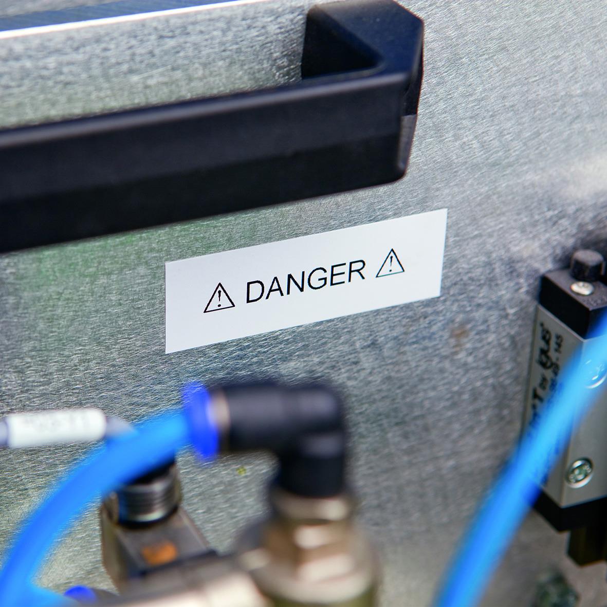 Varningsmärke med text DANGER på en metallskåp med blå och svart utrustning