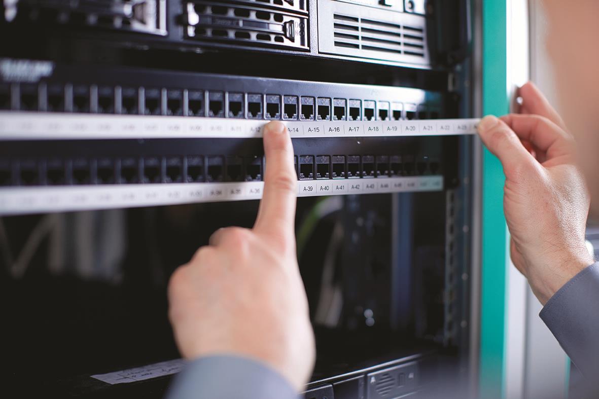 Person som mäter ett Dymo polyester permanent märkbands 9mm svart/vit 5,5m i ett elskåp