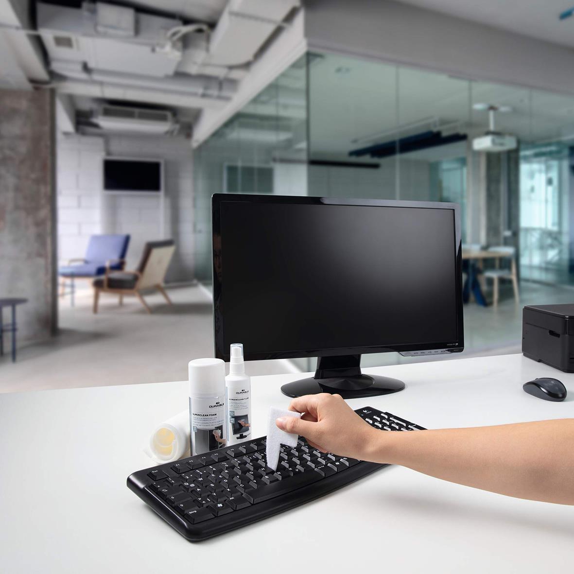 Person rengör en dator med rengöringsset på ett kontorsbord i ett modernt kontorsutrymme