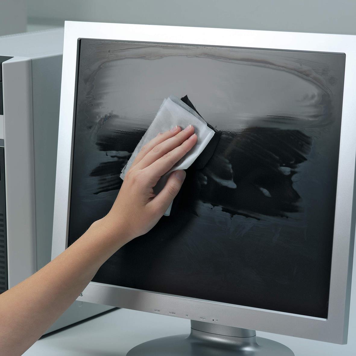 Person rengör en datorskärm med en rengöringsduk