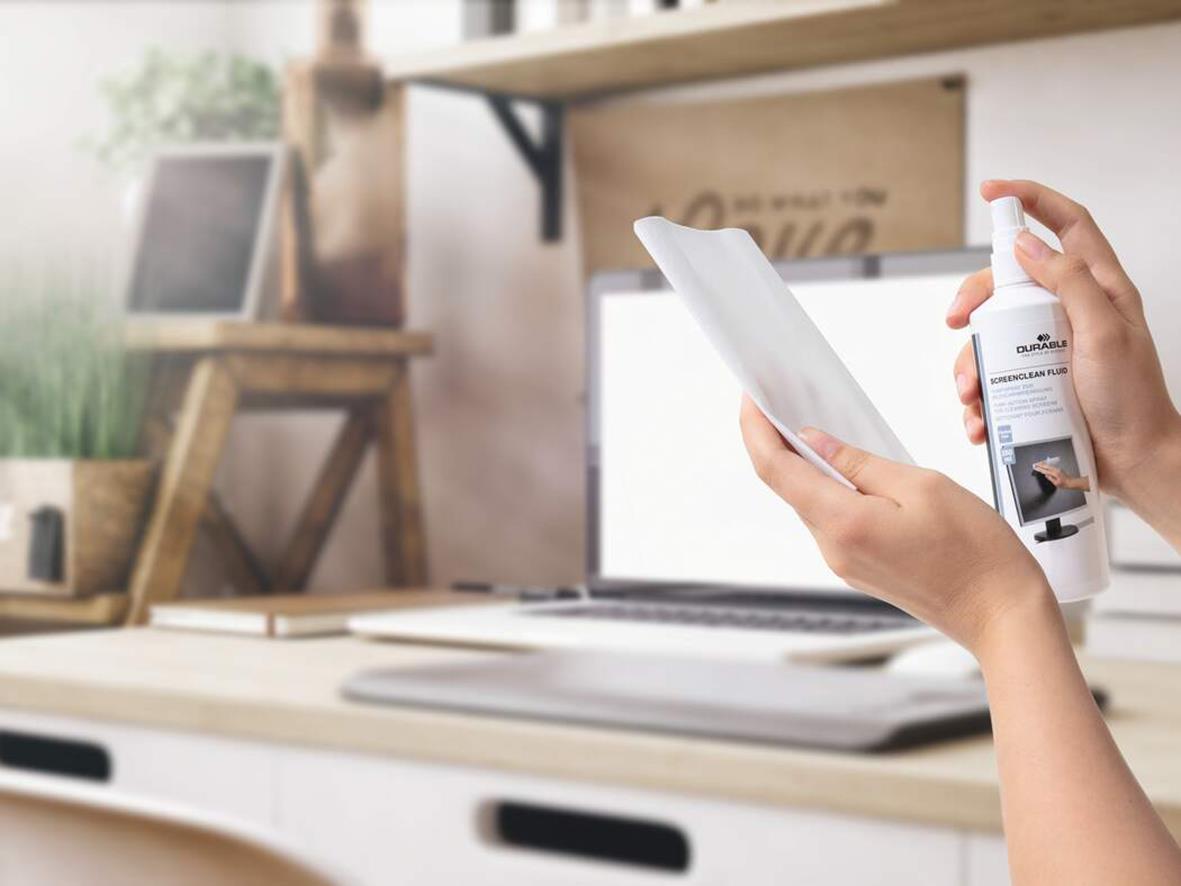 Person som rengör en datorskärm med Durable Screenclean 250ml spray i ett hemmakontor