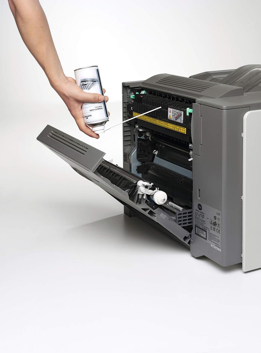 Person använder tryckluftsspray för att rengöra insidan av en skrivare eller kopiator