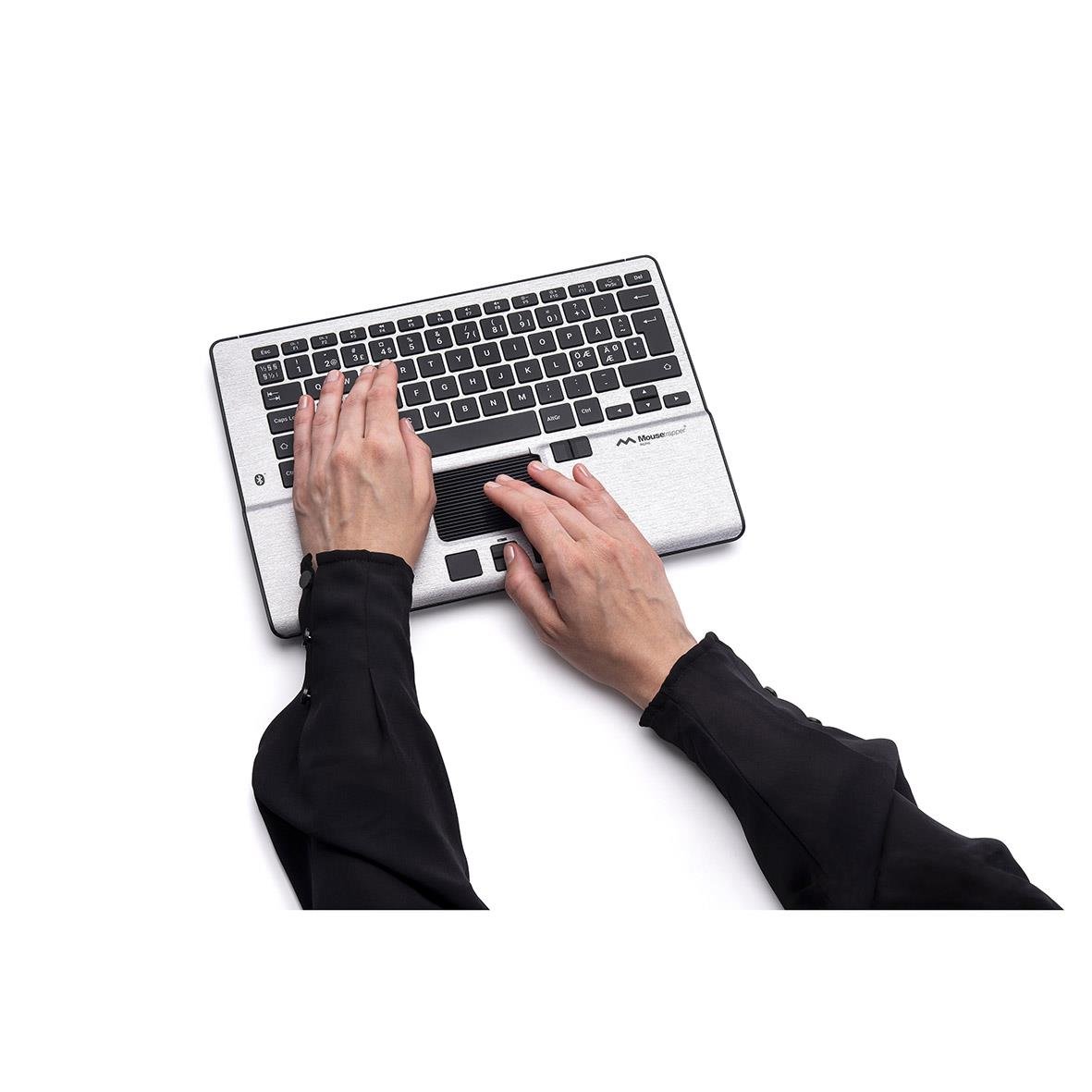 Person använder en ergonomisk trådlös mus på ett laptopbord