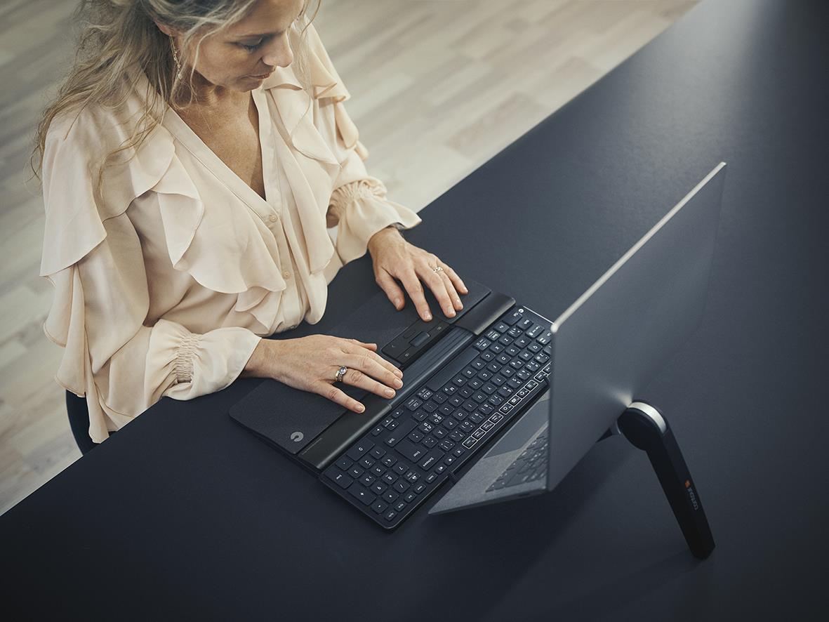Kvinna använder tangentbord Contour Balance BK med sladd vid skrivbord