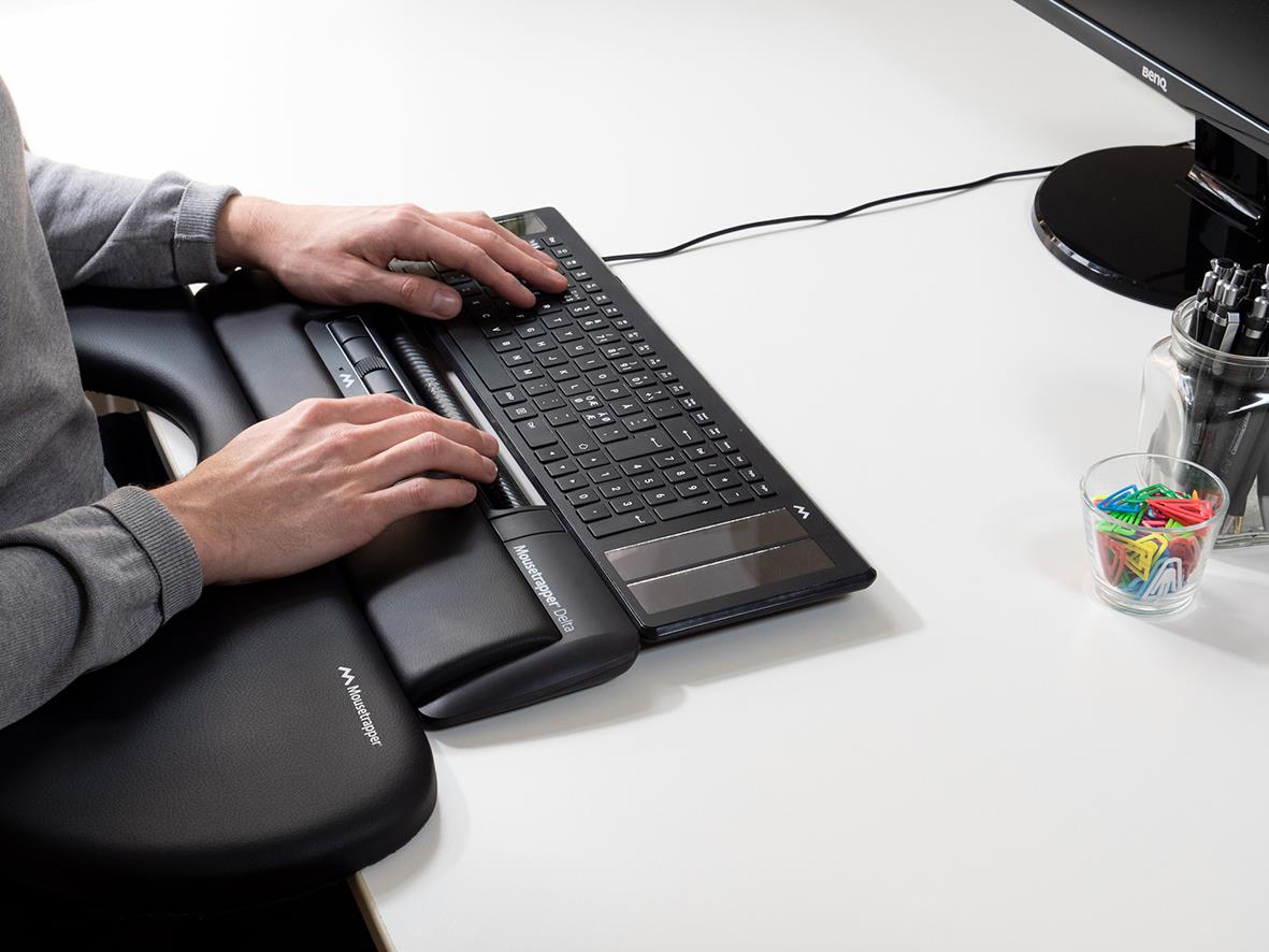 Person använder en ergonomisk mus och tangentbord på skrivbordet