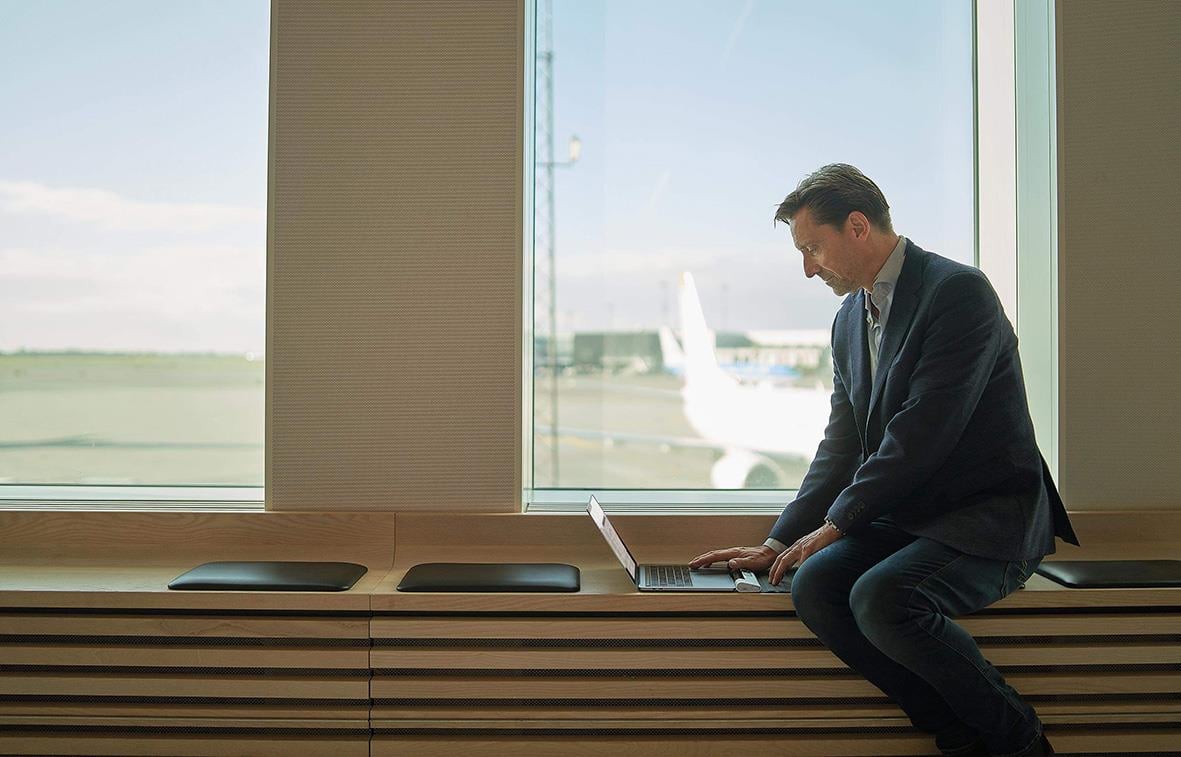 Man i kostym använder trådlös ergonomisk mus på fönsterbänk med flygplan utanför