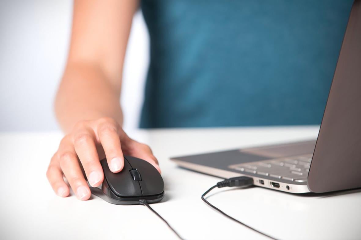Person använder en mus kopplad till en laptop med sladd