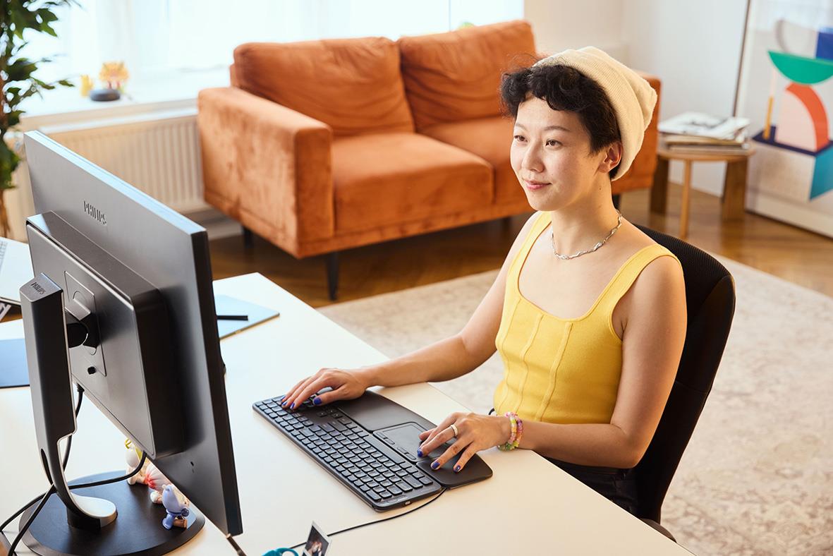 Ung kvinna använder ergonomisk mus Contour Touch med sladd framför dator i vardagsrum