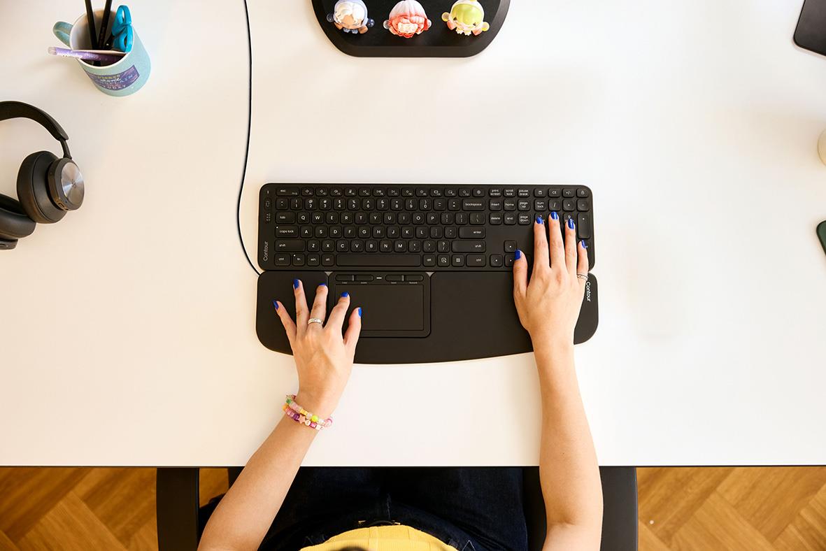 Person som använder en ergonomisk mus Contour Touch med sladd på skrivbord
