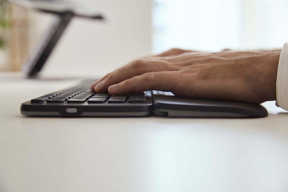 Person som använder ett trådlöst fullstort tangentbord på ett skrivbord