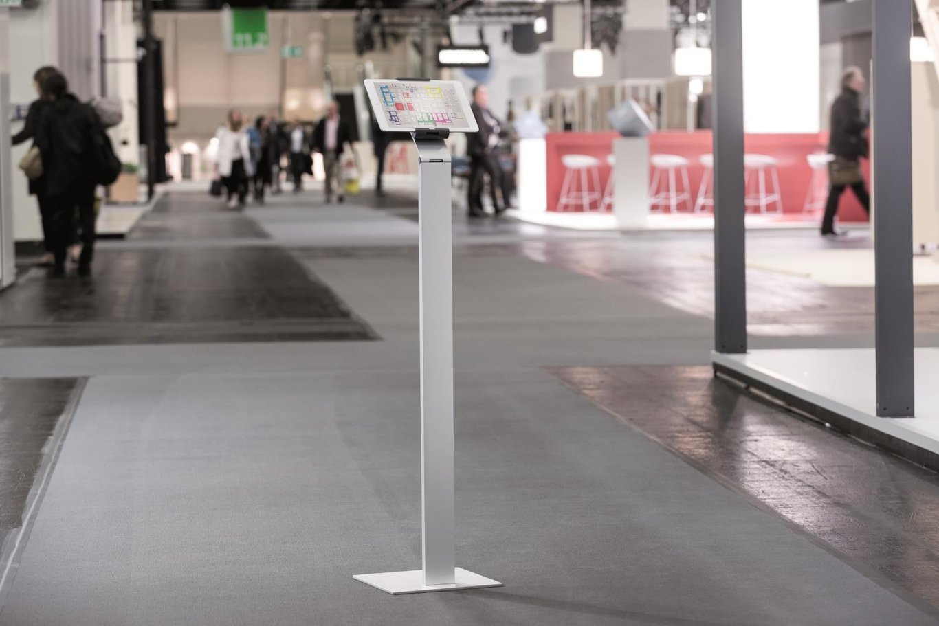 Golvställ för surfplatta på golvet i en offentlig plats med människor i bakgrunden