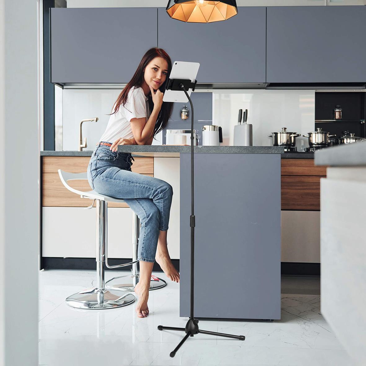 " använder surfplattehållare Twist Golv Svart i kök, står vid köksö och tittar på surfplatta"