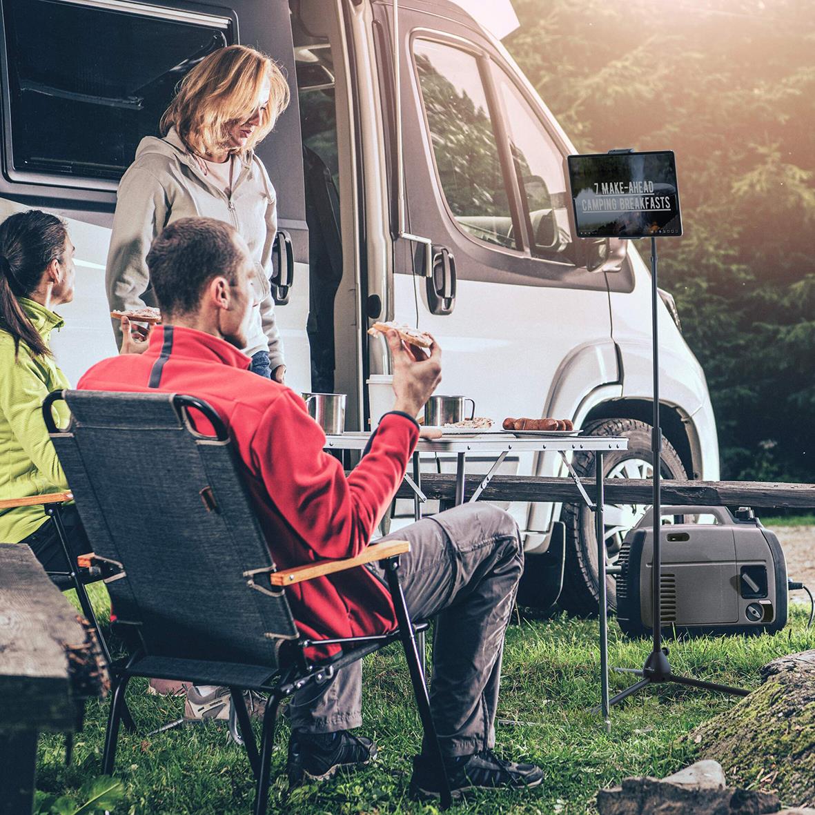 " personer som äter utomhus vid en campingbil, en person som filmar eller tar bilder, och en surfplattehållare Twist Golv Svart synlig"