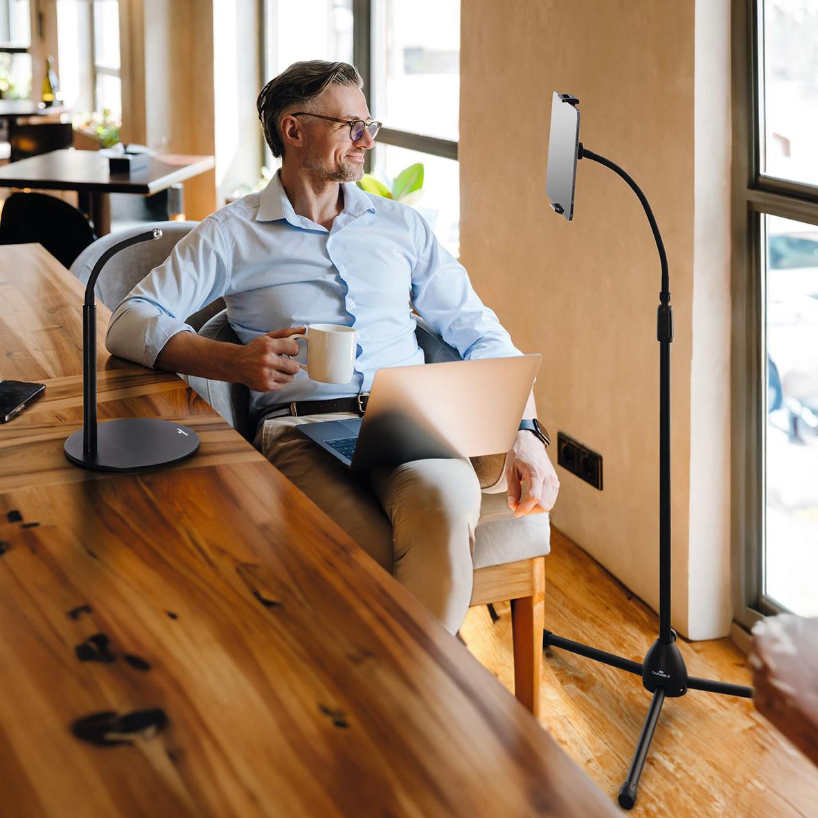 Man med laptop och kaffekopp använder surfplattehållare Twist Kombi Svart i ett café