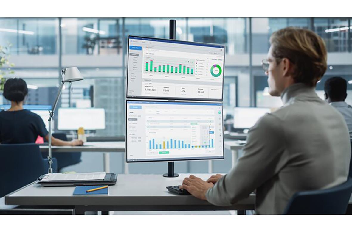 Person som tittar på en stor datorskärm med diagram och statistik i ett modernt kontorslandskap