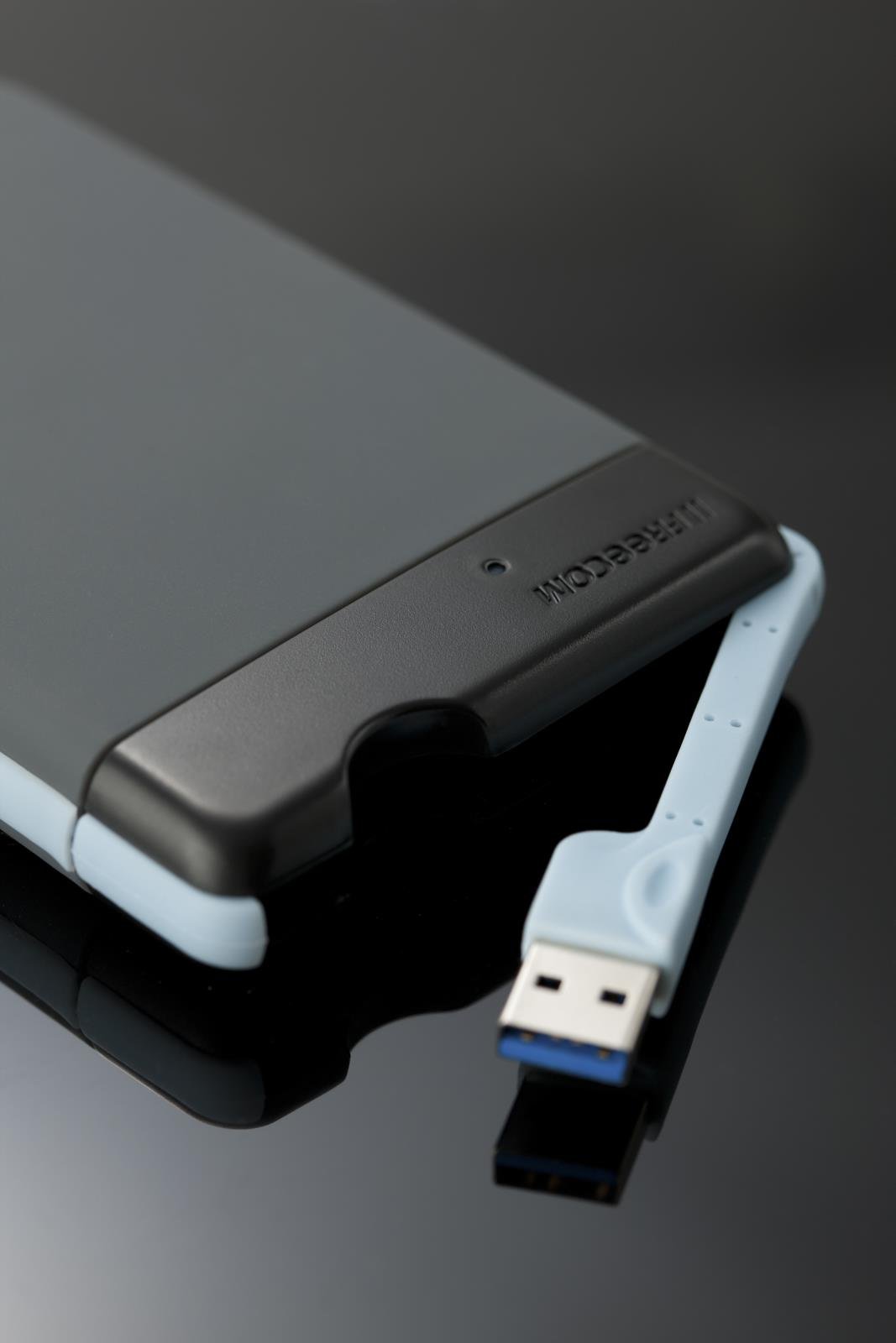 Hårddisk Freecom Mobile ToughDrive 1TB med USB-kabel på svart yta