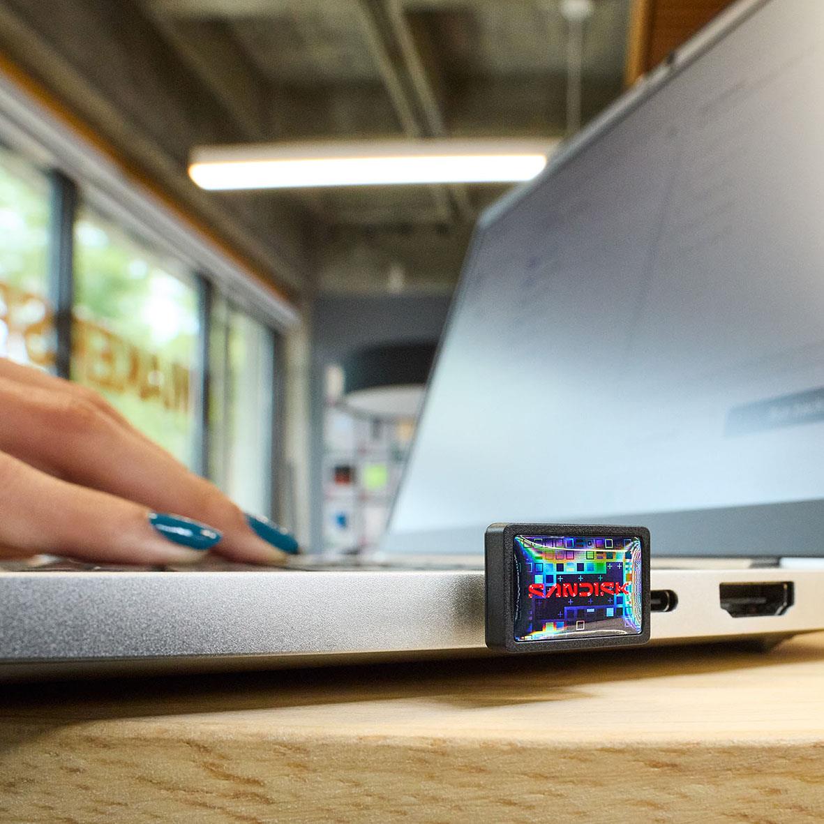 USB-minne Sandisk Extreme Fit 3.2 256GB placerad på en laptop vid ett skrivbord