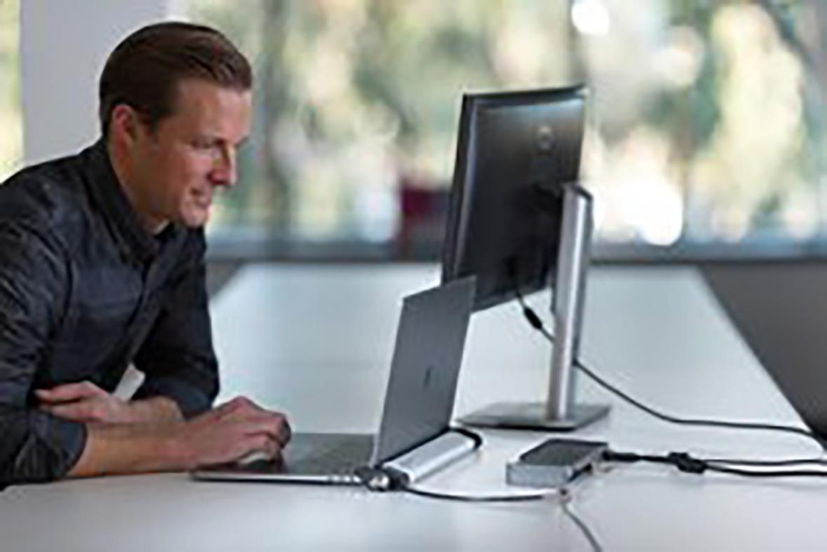 Man använder en låsbar station Kensington 2.0 för MacBook på ett skrivbord