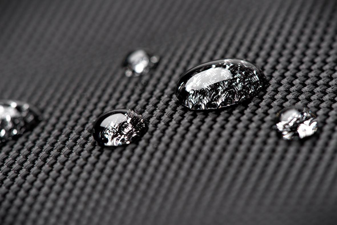 Närbild av vattendroppar på en svart texturerad ryggsäck