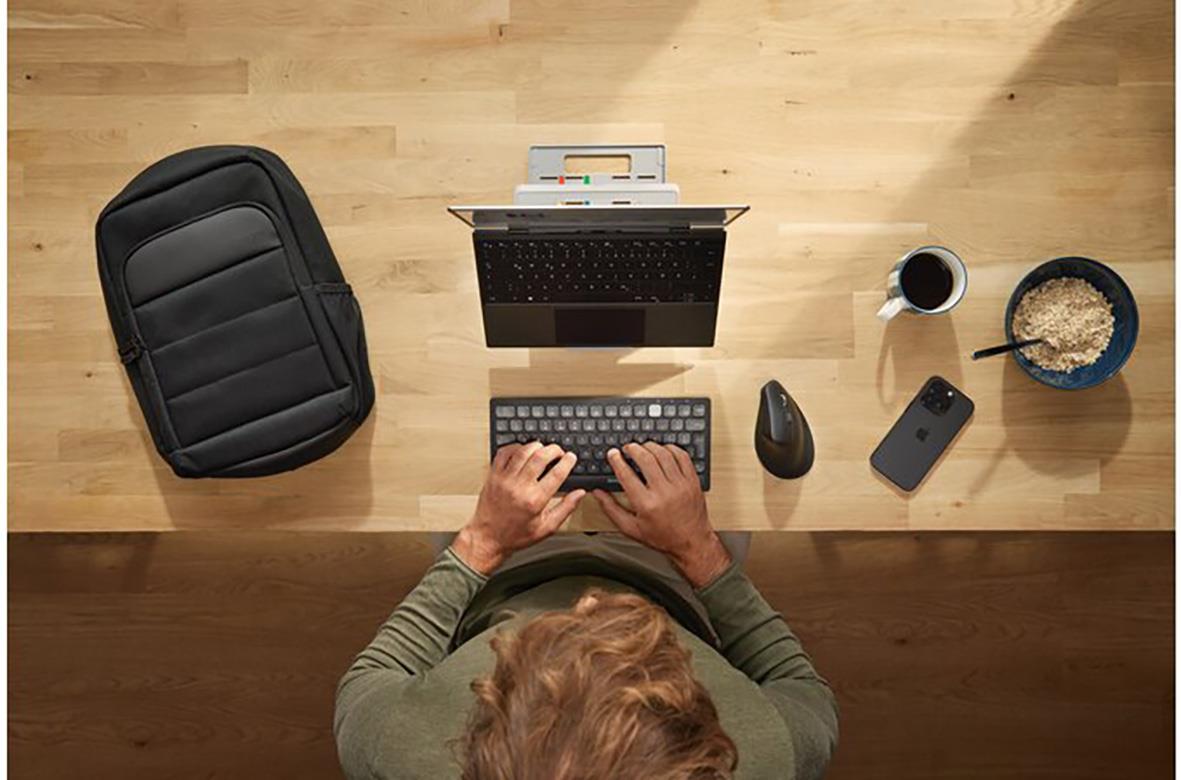 Svart Kensington EQ 16 tum ryggsäck på ett träbord med dator, tangentbord, mus, telefon och mat