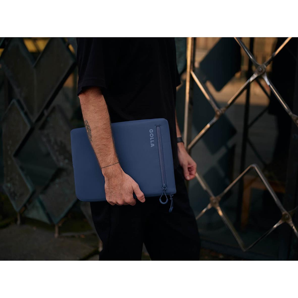 Person håller ett blått neopren datorfodral för 13 tum med dragkedja och Golla-logga