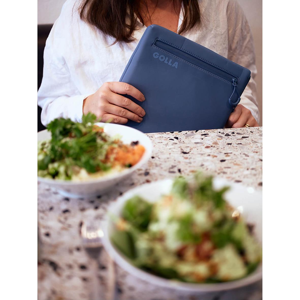 Kvinna håller ett blått neopren datorfodral Golla Metro Petroleum för 13 tum