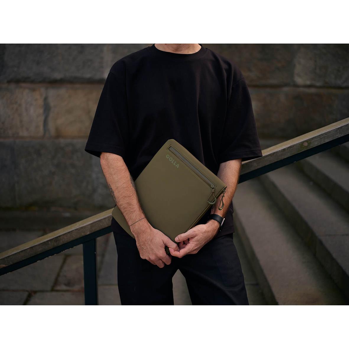 Person som håller ett grönt neopren datorfodral för 13 tum, Golla Metro, utomhus vid en trappa