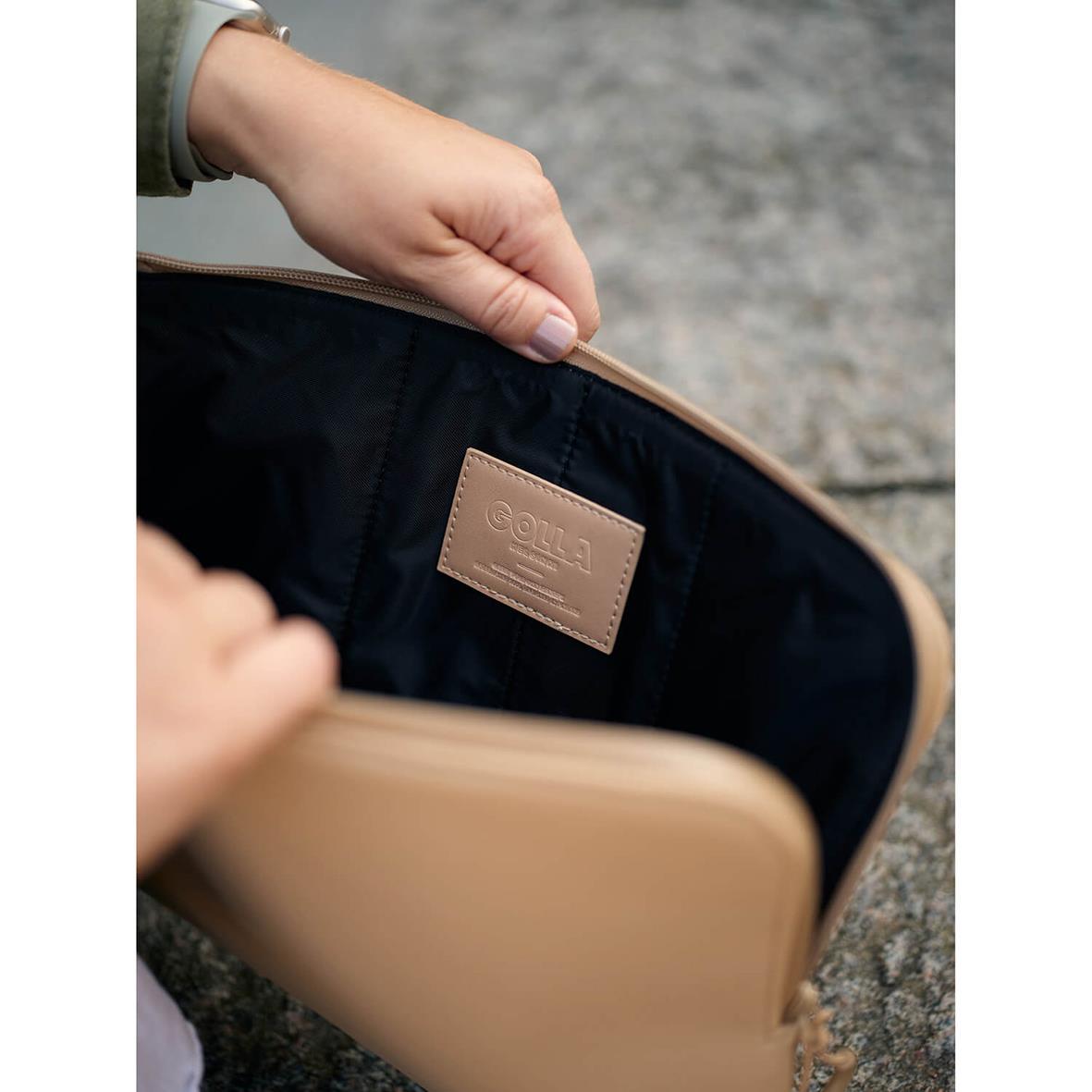 Närbild på ett beige datorfodral i neopren med Golla-märke, öppnat för att visa insidan, på en grå yta