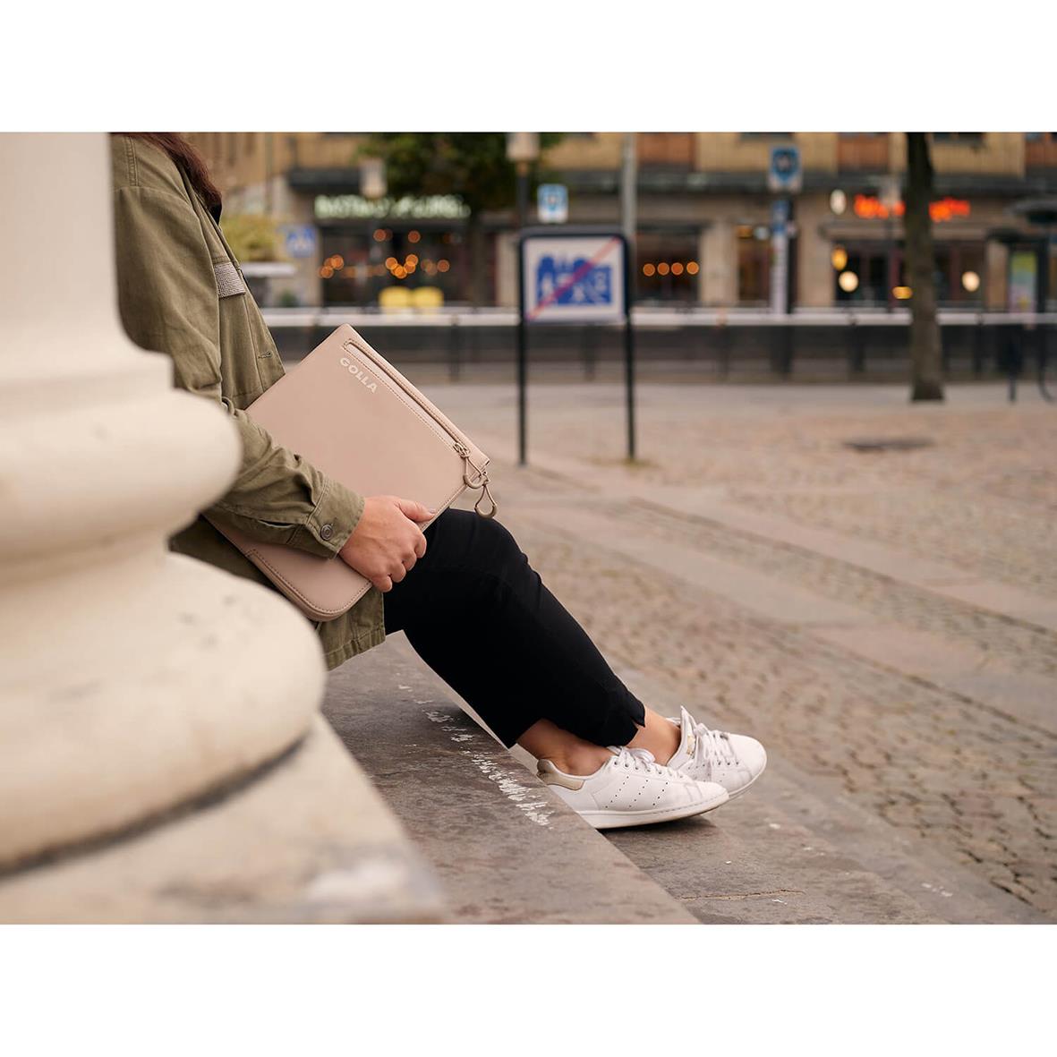 Person som sitter på en stadsgata med ett rosa datorfodral Golla Metro Neopren Cream 13 tum