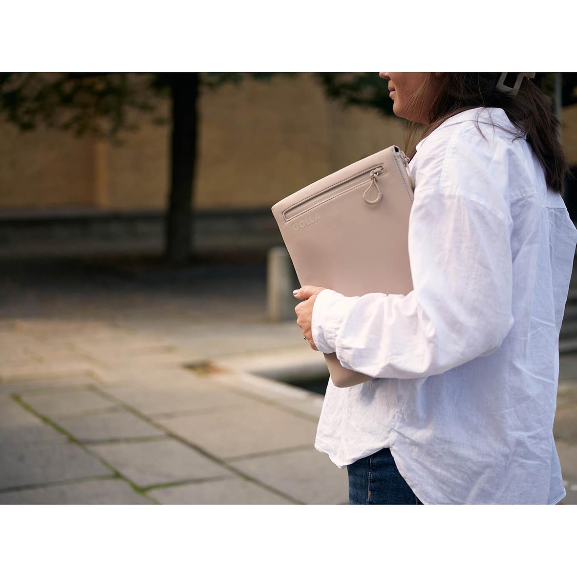 Kvinna håller ett beige neopren datorfodral Golla Metro Cream 13 tum utomhus