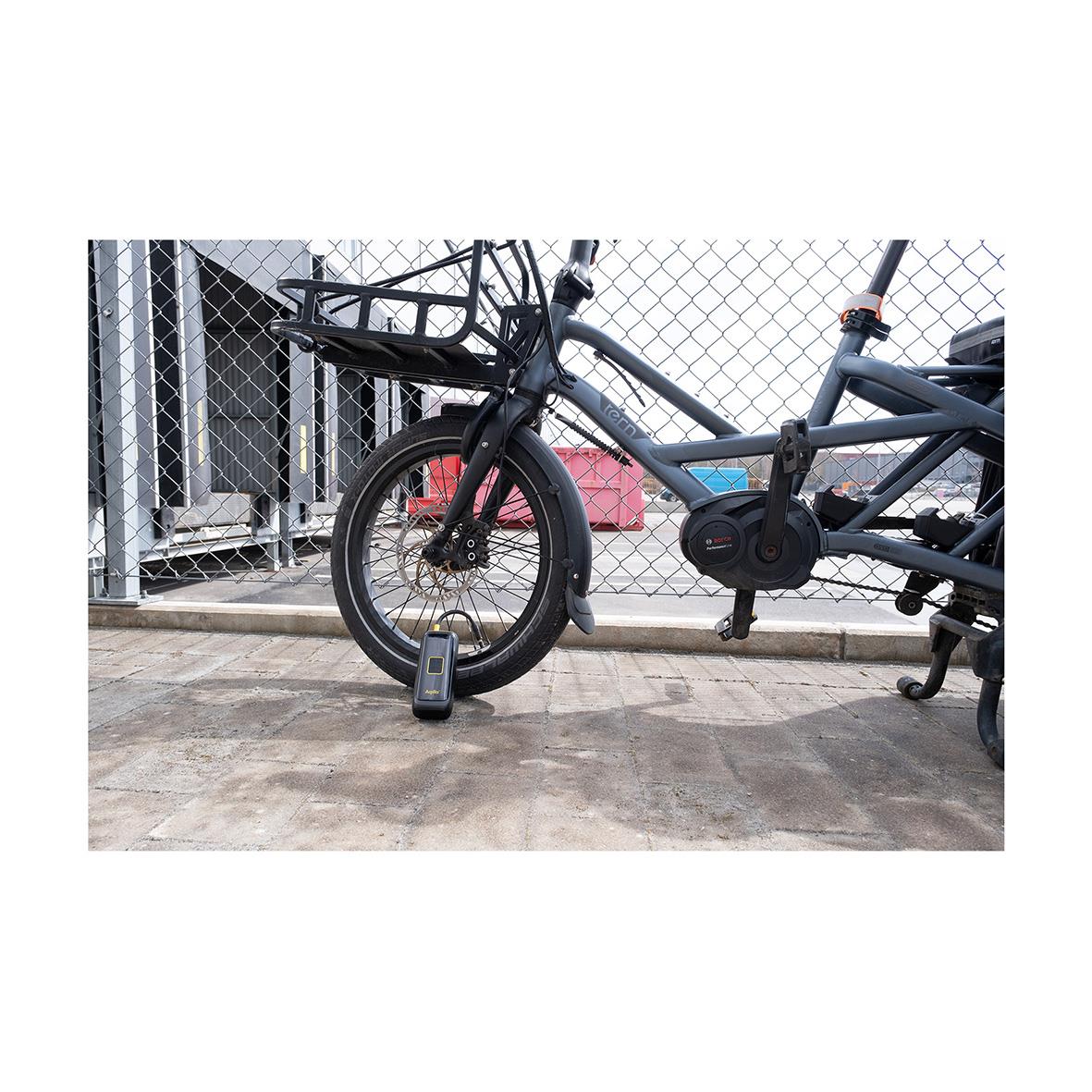 Batteridriven luftpump Aqiila Airbird C4 kopplad till elcykel framför ett stängsel