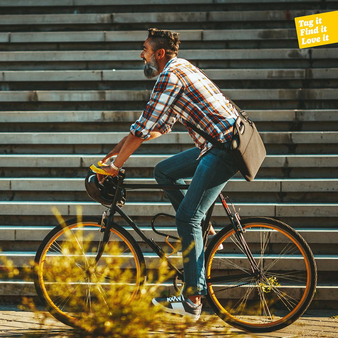 Man cyklar uppför trappa med stadstrappa i bakgrunden, gul varningsskylt i hörnet