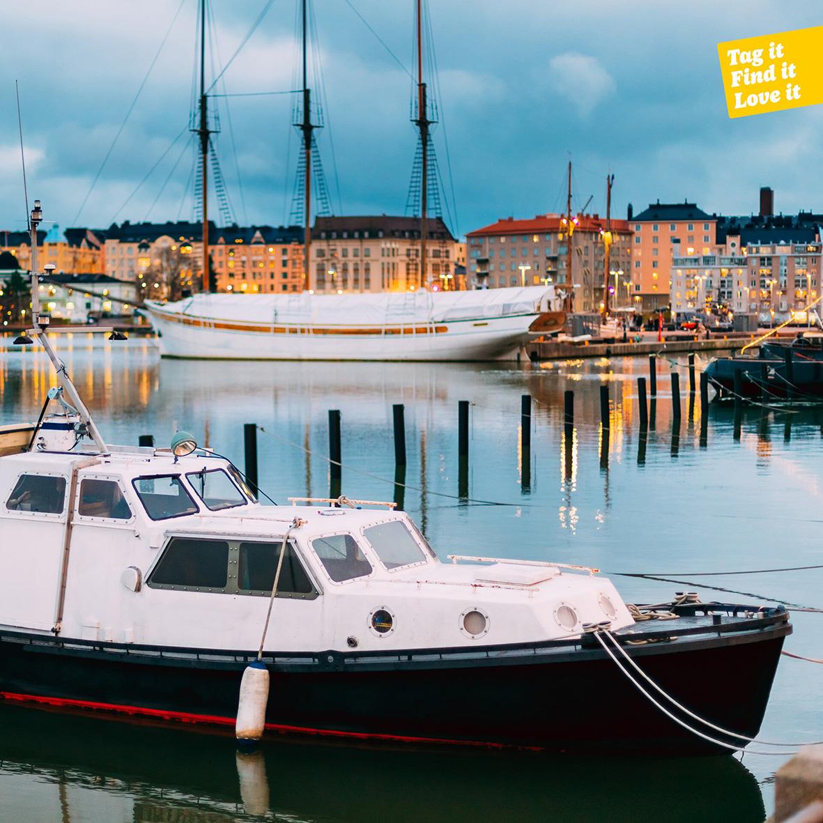 Båt i hamn med stadsvy och molnigt väder i bakgrunden