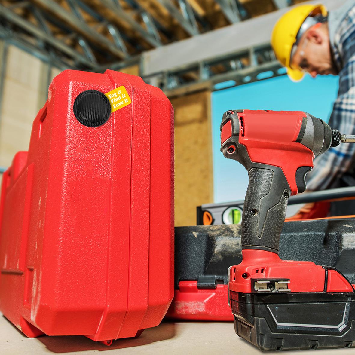 Röd tracker med monteringshölje och en svart och röd trådlös skruvdragare på en byggarbetsplats