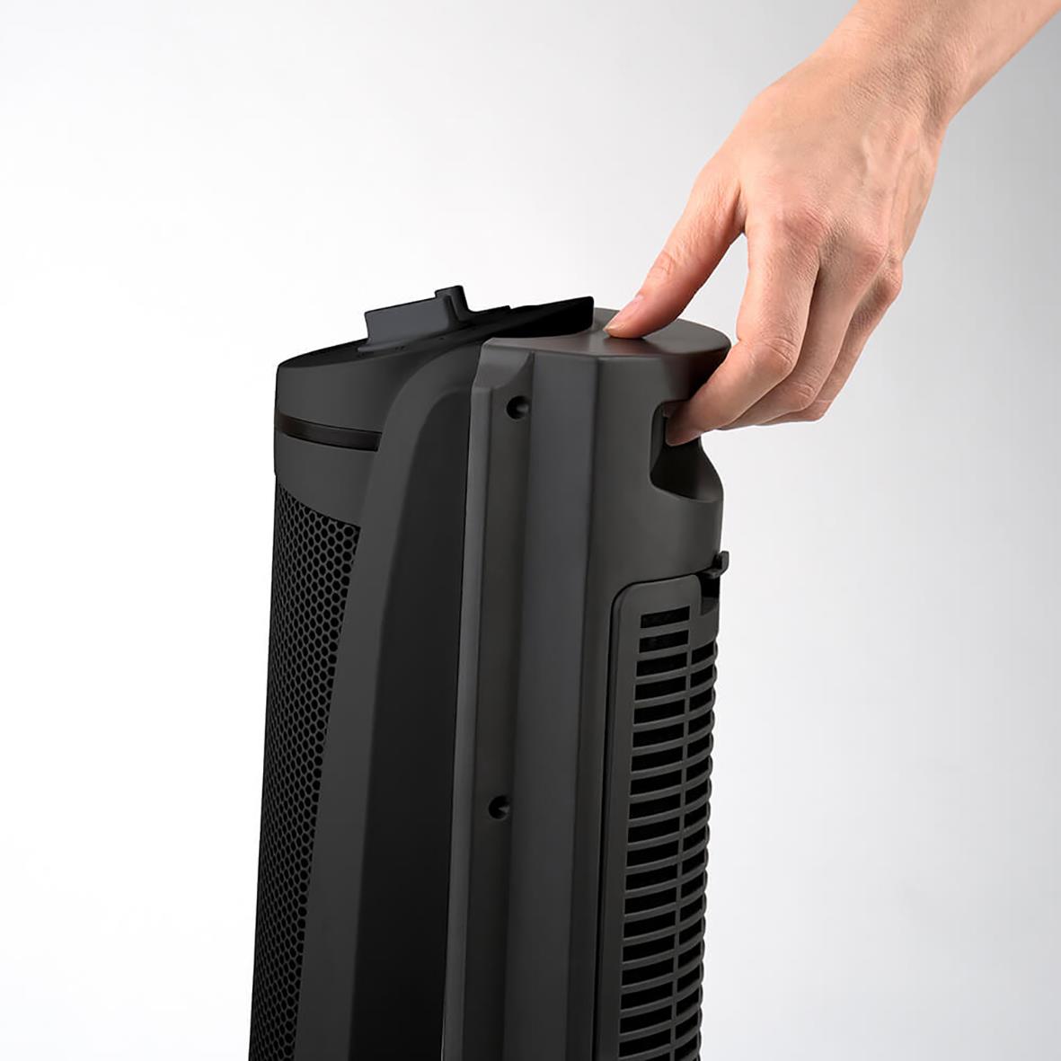 Hand som håller en svart keramisk tornvärmare Black+Decker 2000W