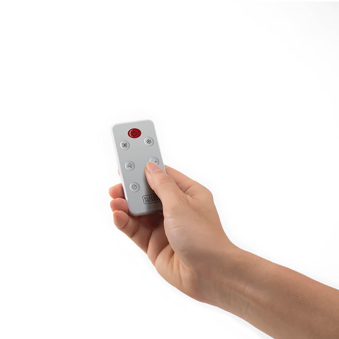Hand som håller en fjärrkontroll med knappar för luftkylare Black+Decker BXAC50x vit mot en vit bakgrund