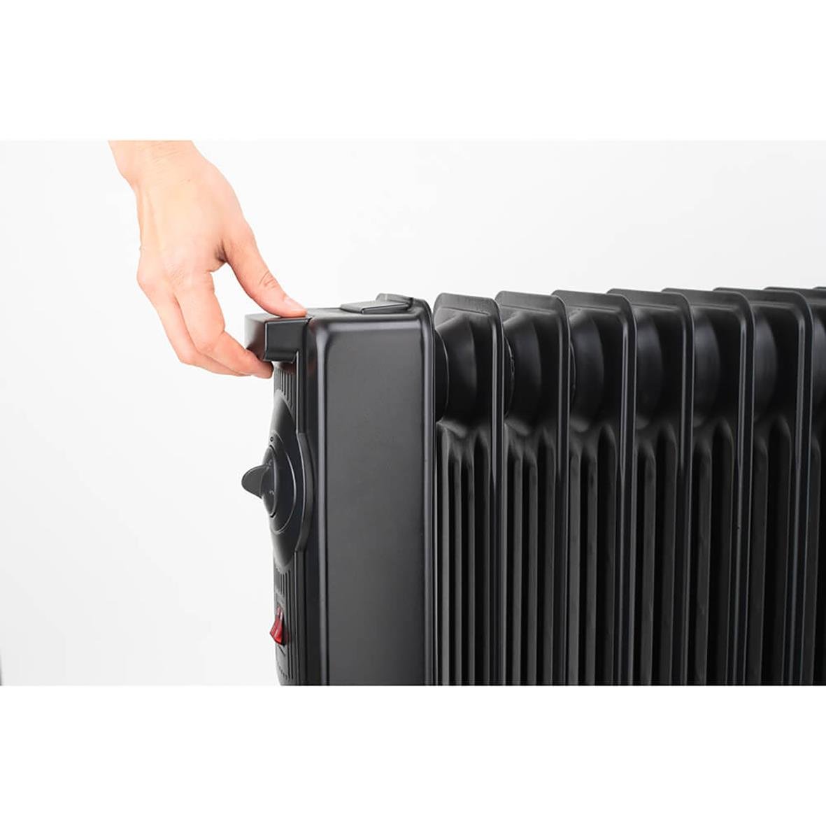 Hand som justerar en svart Element Black+Decker 1500W oljefylld radiator